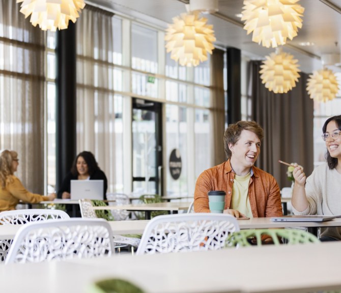 Henkilöitä pöydän ääressä ruokalassa.