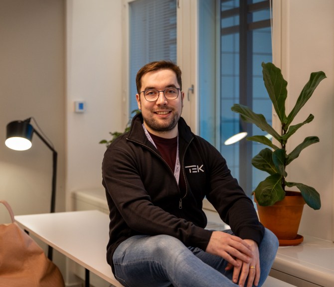 Owain Hopeaketo istuu toimiston pöydän kulmalla.