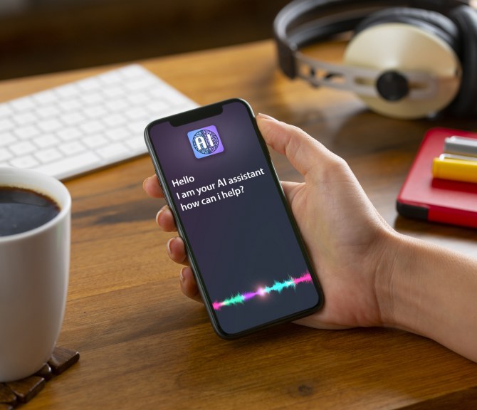 Henkilö pitelee puhelinta kädessään. Ruudulla tekoälyassistentti.
