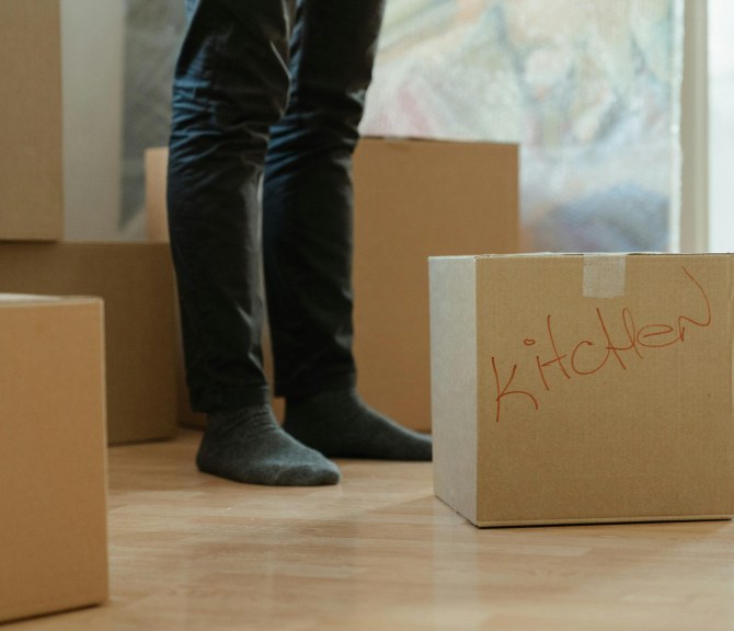 Henkilö seisoo muuttolaatikoiden keskellä.