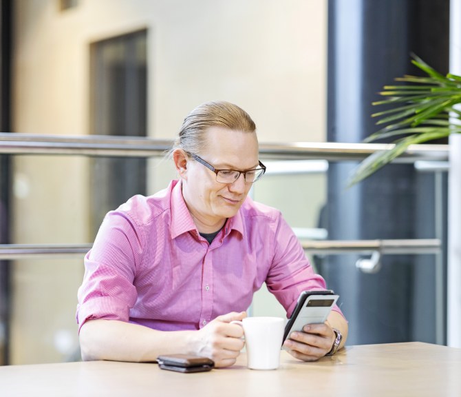 Työntekijä on kahvitauolla ja selaa puhelintaan.