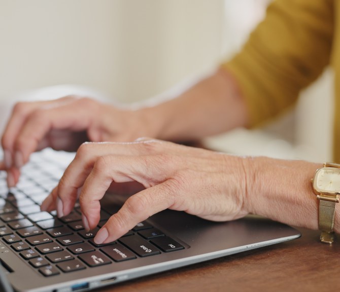 Henkilö keltaisessa paidassa käyttää tietokonetta 