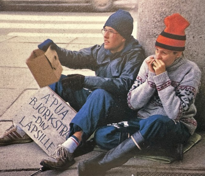 Kaksi nuorta henkilöä istuu maassa keräämässä rahaa.