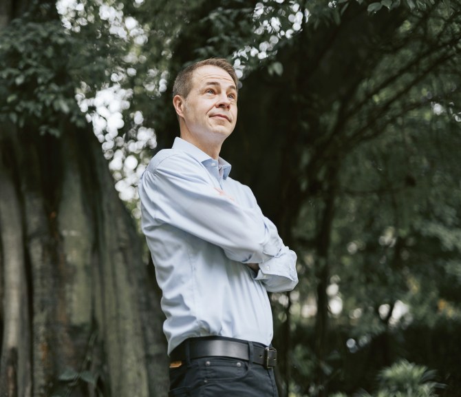 Sami Sivola seisoo isojen puiden edessä kädet puuskassa.