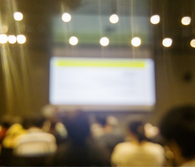 A lecture in an auditorium with bright lights.