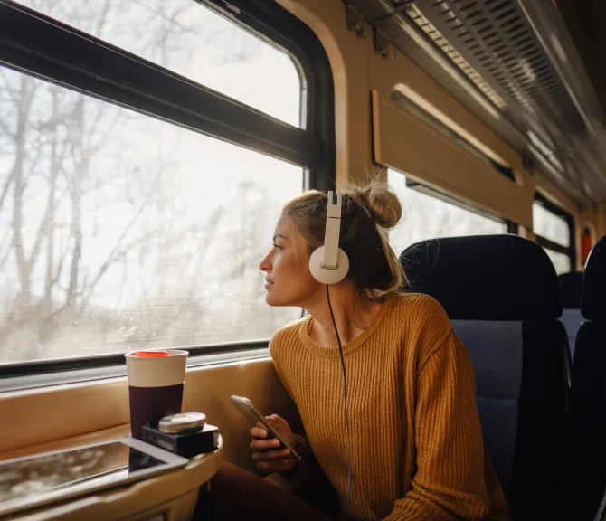 Tyttö istuu junassa ja katsoo ikkunasta ulos