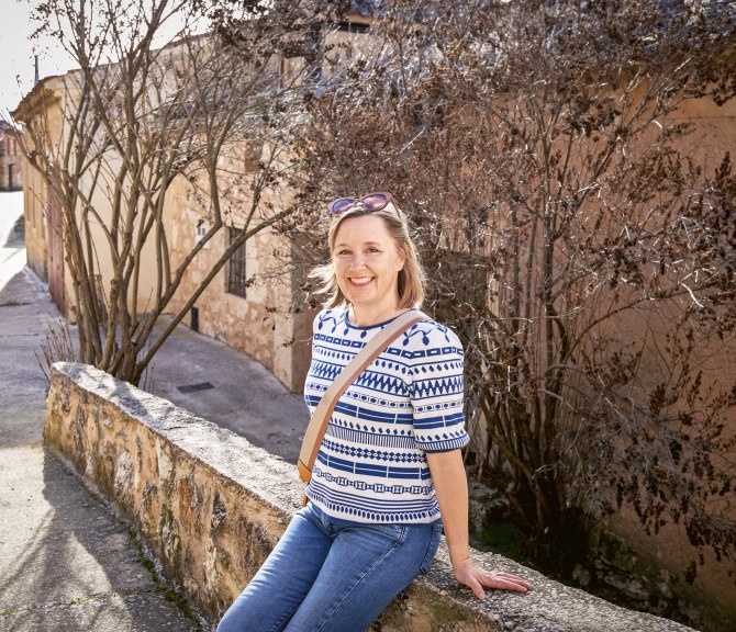 Julia Ahvenainen istuu matalalla muurilla.