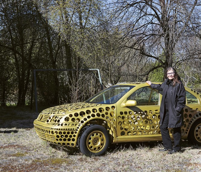 Anna-Kaisa Ant-Wuorinen kultaisen auton vieressä.