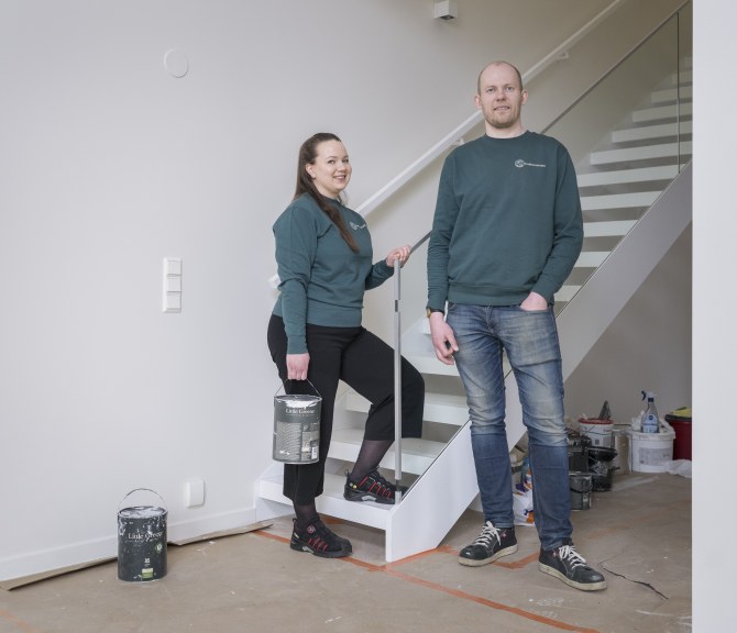 Katariina Laine ja Theo Ruokomaa katsovat kameraan työmaalla.