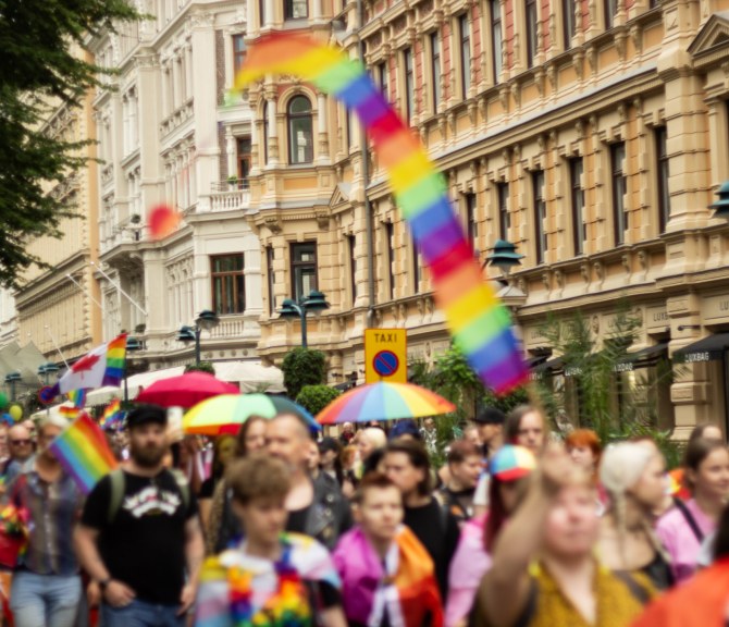Helsinki Pride -kulkue kulkemassa kantakaupungissa. Taustalla näkyy rakennuksia ja etualalla kulkueen osallistujia. 
