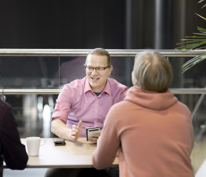 Joukko miehi istuu pöydän ääressä.