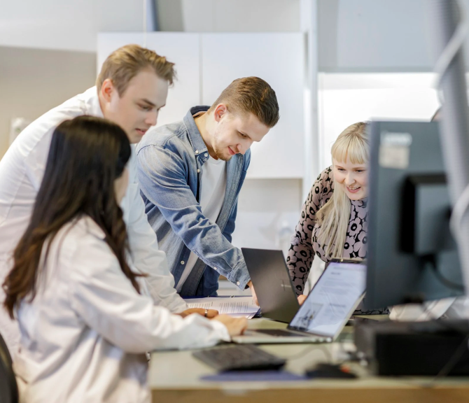 Tiimi on kokoontunut työpöydän äärelle keskustelemaan.