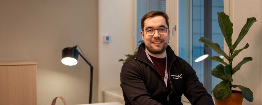 Owain Hopeaketo istuu toimiston pöydän kulmalla.