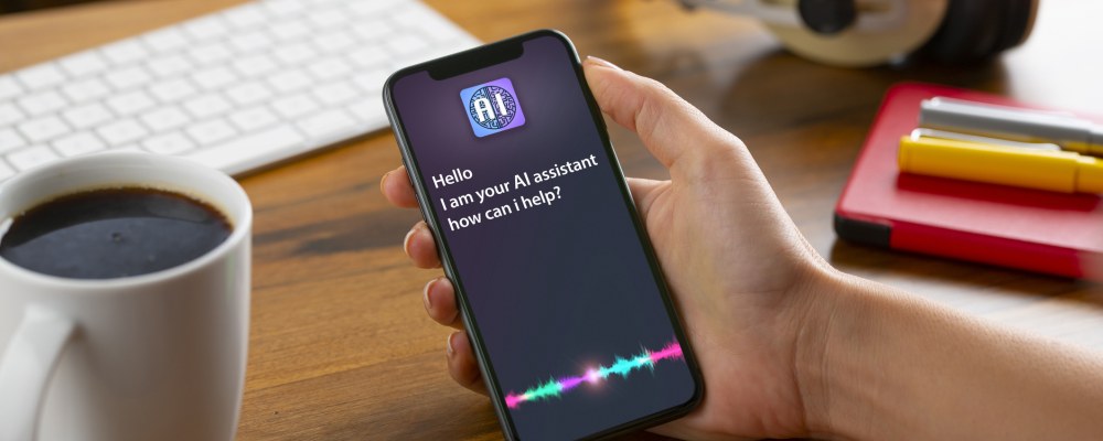 Henkilö pitelee puhelinta kädessään. Ruudulla tekoälyassistentti.