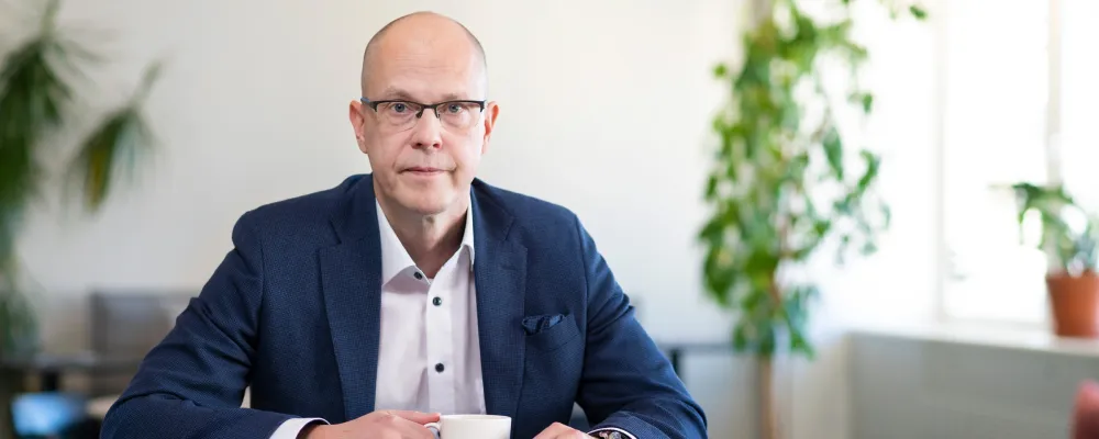 Teemu Hankamäki katsoo kameraan työpöydän ääressä.