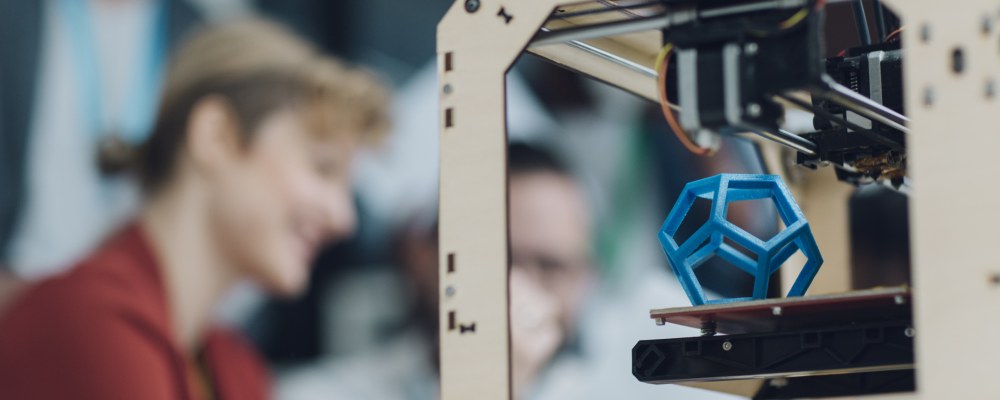 Edessä 3D-printteri, takana tiimi.