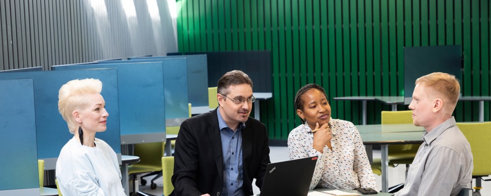 Henkilöitä keskustelemassa pöydän ääressä.