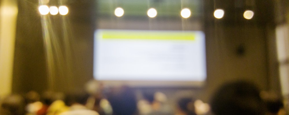 A lecture in an auditorium with bright lights.
