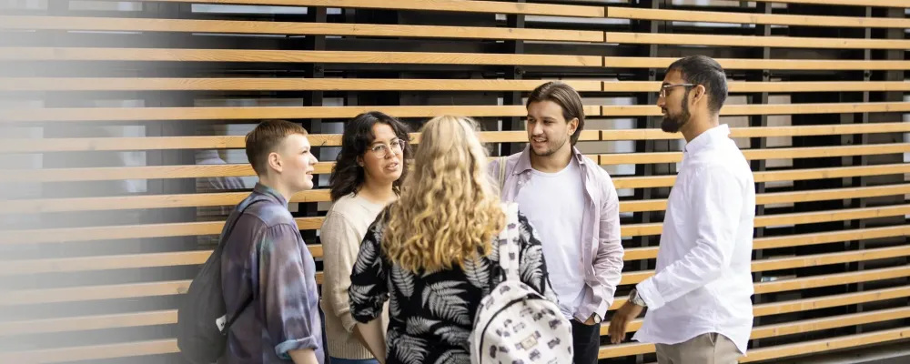 Opiskelijoita keskustelemassa rimaseinän edessä