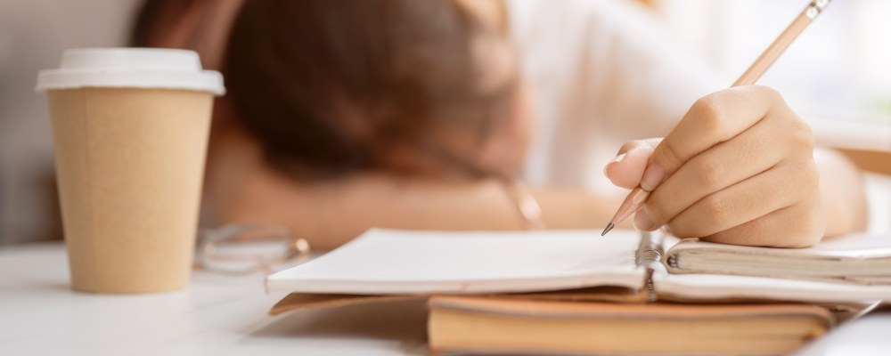 A tired student, a cup of coffee and homework.