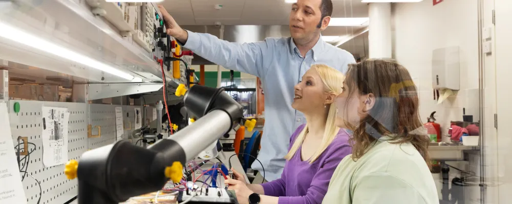 Opettaja ja kaksi opiskelijaa teknisten laitteiden parissa