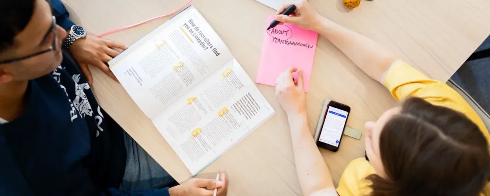 Kaksi henkilöä tarkastelee Työkirjan artikkelia LinkedInistä