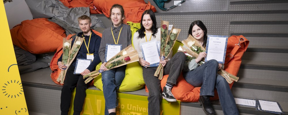 Kipinä-kilpailun voittaneet neljä nuorta istuu vierekkäin portaikossa.