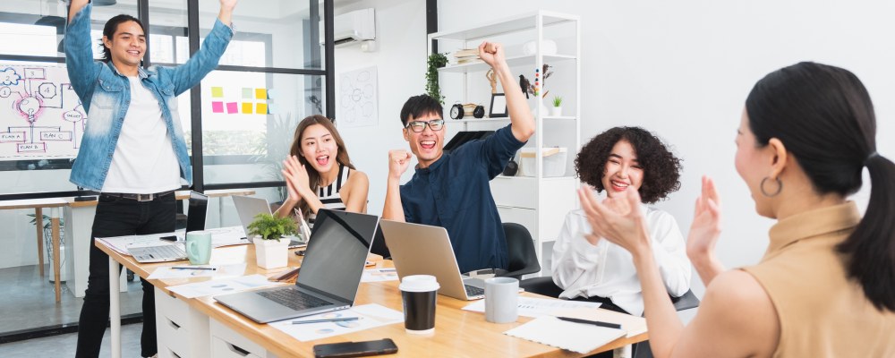 Ihmisiä, kädet ylhäällä, pöytä