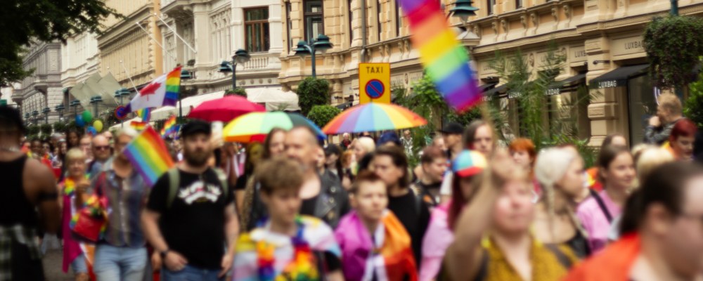 Helsinki Pride -kulkue kulkemassa kantakaupungissa. Taustalla näkyy rakennuksia ja etualalla kulkueen osallistujia. 