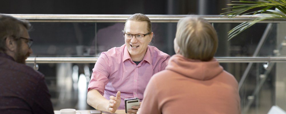 Joukko miehi istuu pöydän ääressä.