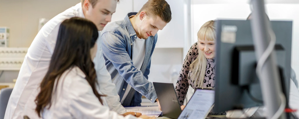 Tiimi on kokoontunut työpöydän äärelle keskustelemaan.