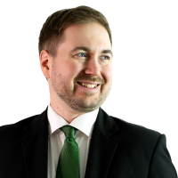 Lauri Lavanti hymyilemässä ja katsomassa oikealle, päällään musta puku, valkoinen kauluspaita ja vihreä kravatti.