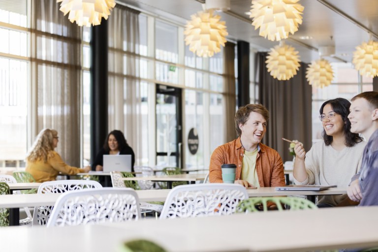 Henkilöitä pöydän ääressä ruokalassa.