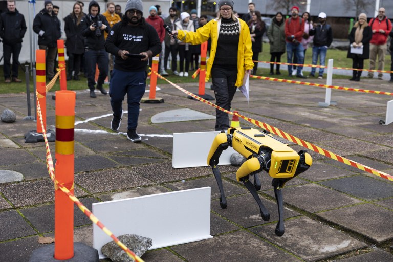 Spot-robottikoira kävelee, takana on yliopistonlehtori Aino Ahtinen.
