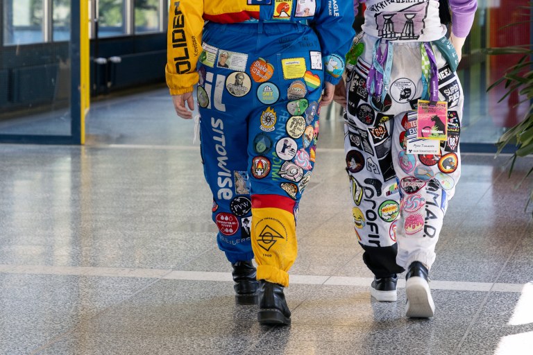 Kaksi haalaripukuista henkilöä kävelee.