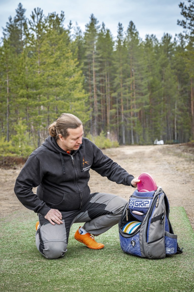 Ville Nivalainen kyykistyneenä frisbeegolf-reppunsa viereen.
