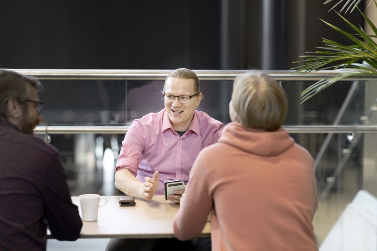 Joukko miehi istuu pöydän ääressä.