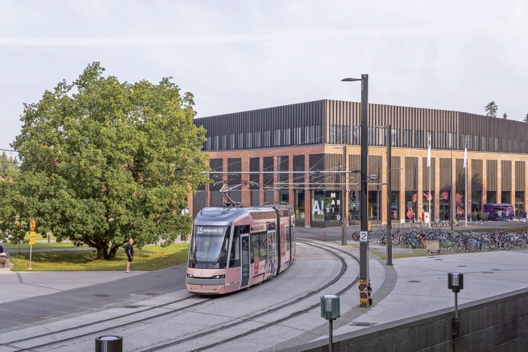 Raitiovaunu kurvaa Otaniemessä puun takaa.