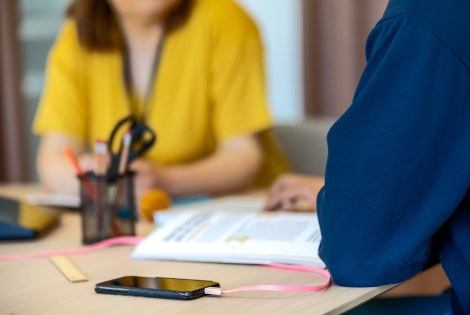 Kaksi henkilöä keskustelee, pöydällä on puhelin ja avoin opas.