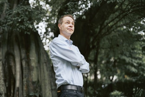 Sami Sivola seisoo isojen puiden edessä kädet puuskassa.