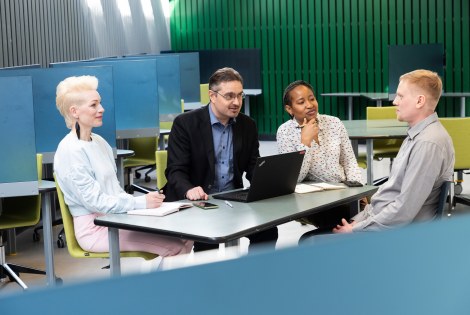 Henkilöitä keskustelemassa pöydän ääressä.