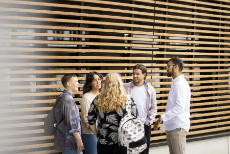 Opiskelijoita keskustelemassa rimaseinän edessä