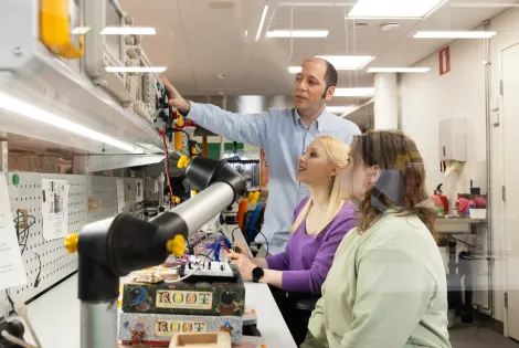 Opettaja ja kaksi opiskelijaa teknisten laitteiden parissa