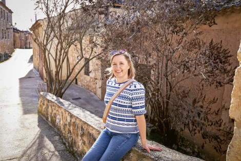 Julia Ahvenainen istuu matalalla muurilla.