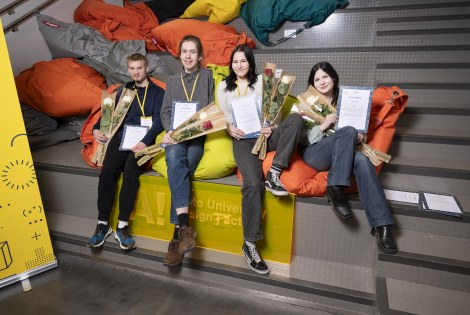 Kipinä-kilpailun voittaneet neljä nuorta istuu vierekkäin portaikossa.