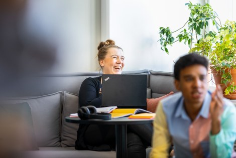 Kaksi henkilöä lounge-tilassa, taaimmainen iloitsee.