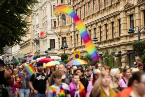 Helsinki Pride -kulkue kulkemassa kantakaupungissa. Taustalla näkyy rakennuksia ja etualalla kulkueen osallistujia. 