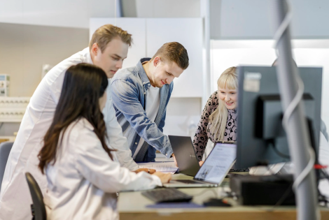Tiimi on kokoontunut työpöydän äärelle keskustelemaan.