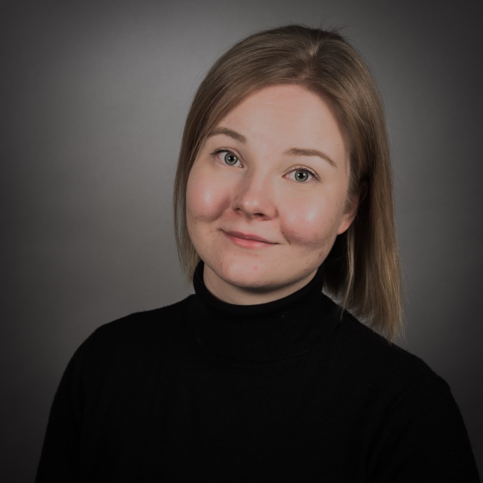 Kuva Senni Auvisesta. Tausta on tummanharmaa. Musta pitkähihainen paita, lyhyet vaaleat hiukset