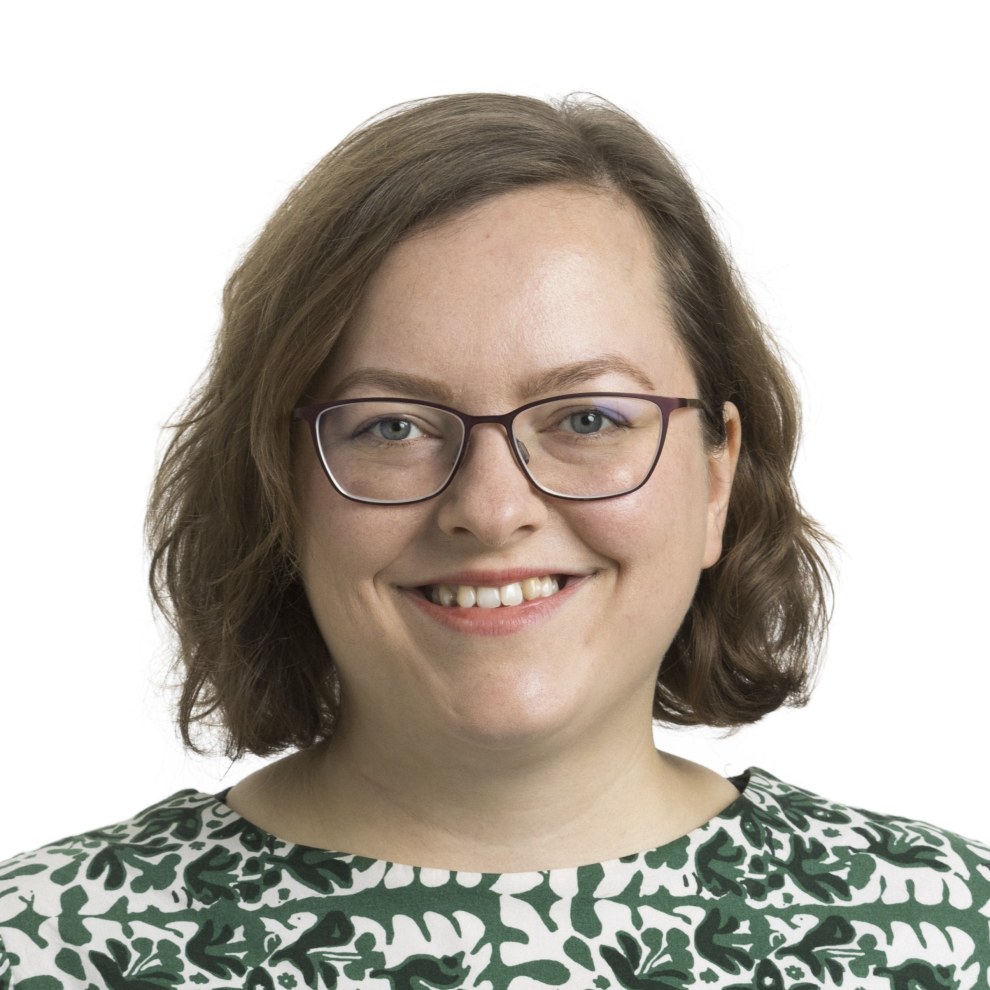 Saana Rossin kasvokuva. Hänellä on hymyilevä ilme, silmälasit ja ruskea polkkatukka.